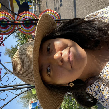 Portrait of Alma Urbano wearing a straw sun hat