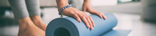 Close up of hands rolling up a blue yoga mat