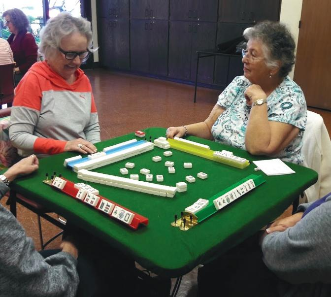 A group of older adults playing Mahjong at a table.