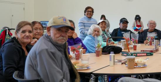 A diverse group of older adults sitting around a large table at the community center