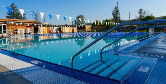 Wide view of the Terra Linda Community Pool with lap lanes and blue-and-white flags overhead.
