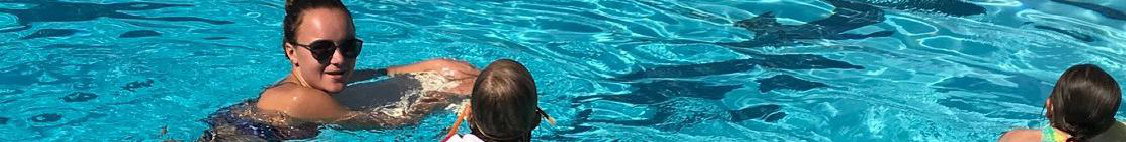 People swimming in a clear blue pool.