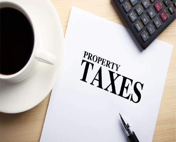 Property taxes document with a coffee cup, calculator, and pen