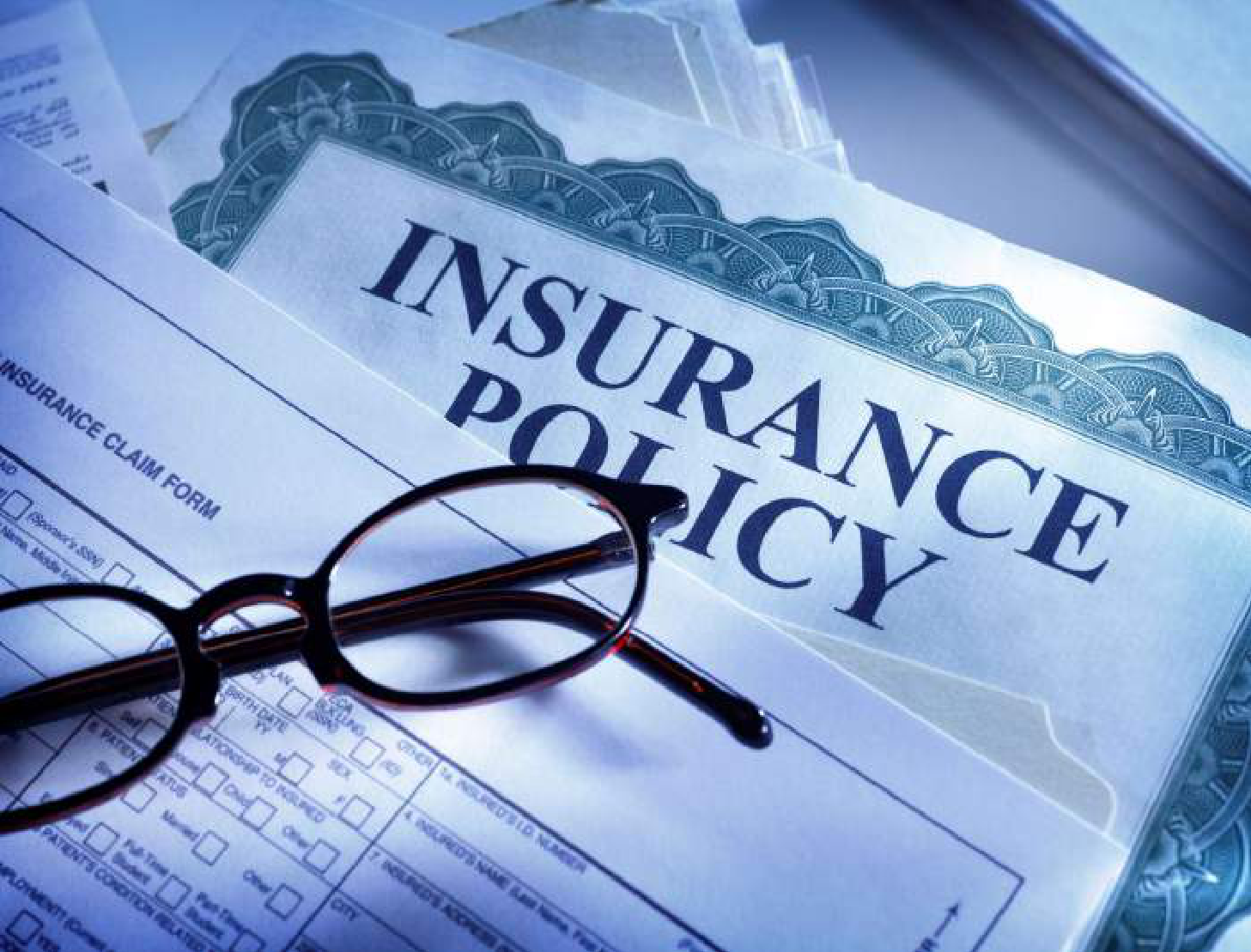 Insurance policy documents and claim form with reading glasses