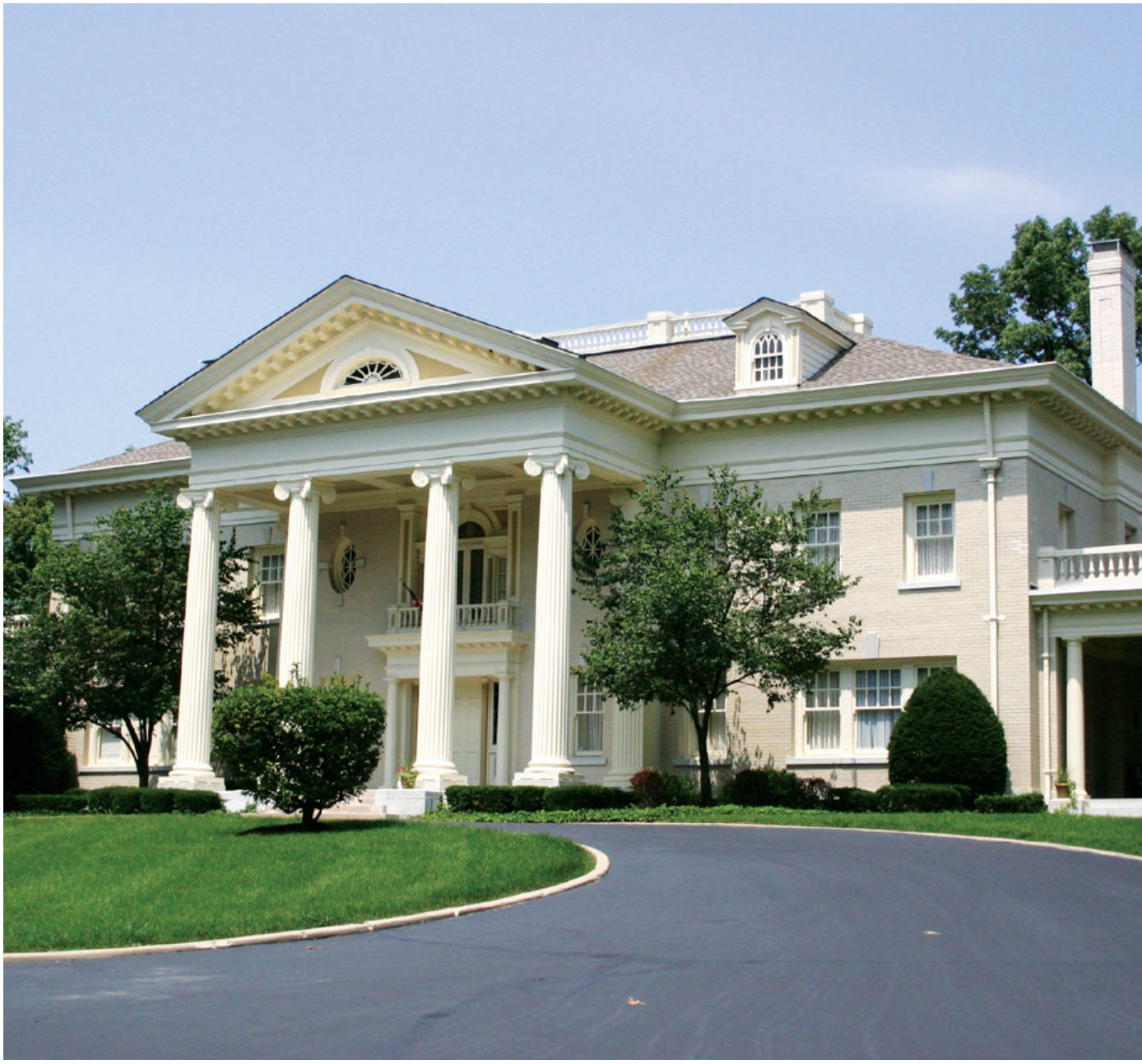 White mansion with classical columns and driveway