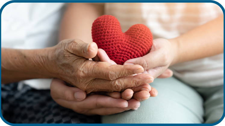 Hands holding a small red crocheted heart supporting care and community services