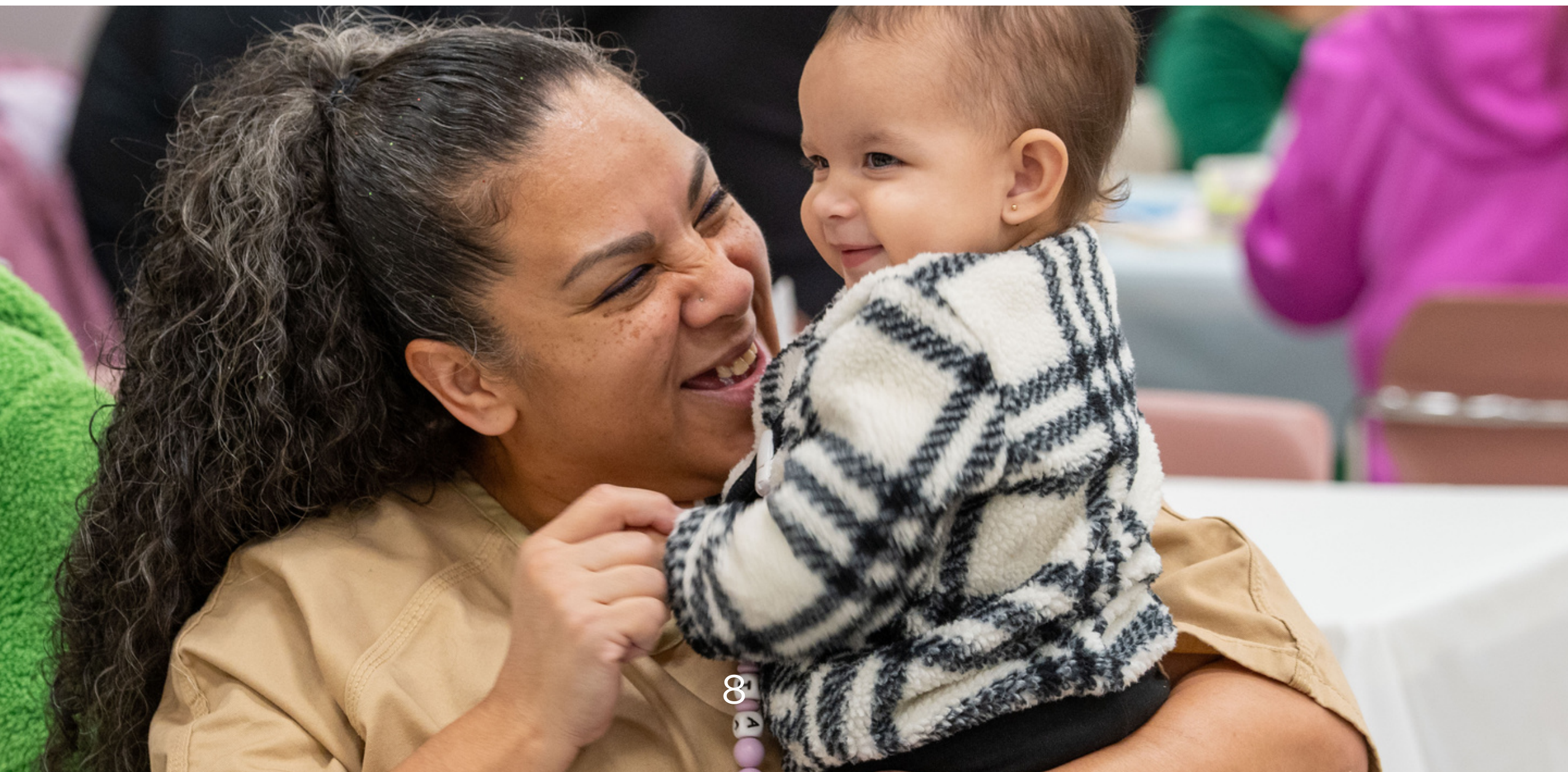 Incarcerated mother smiling warmly as she holds her smiling infant child