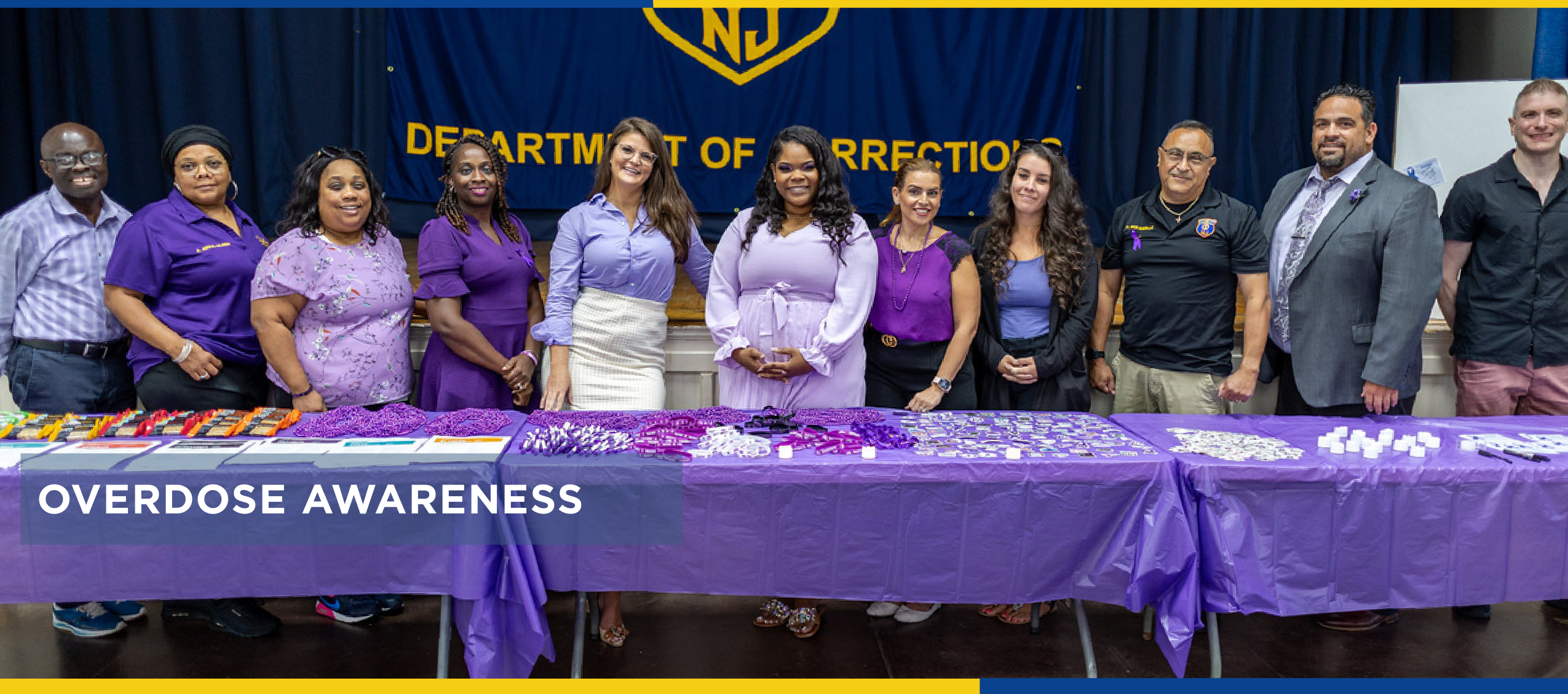 Department of Corrections staff wearing purple standing together behind a table for Overdose Awareness