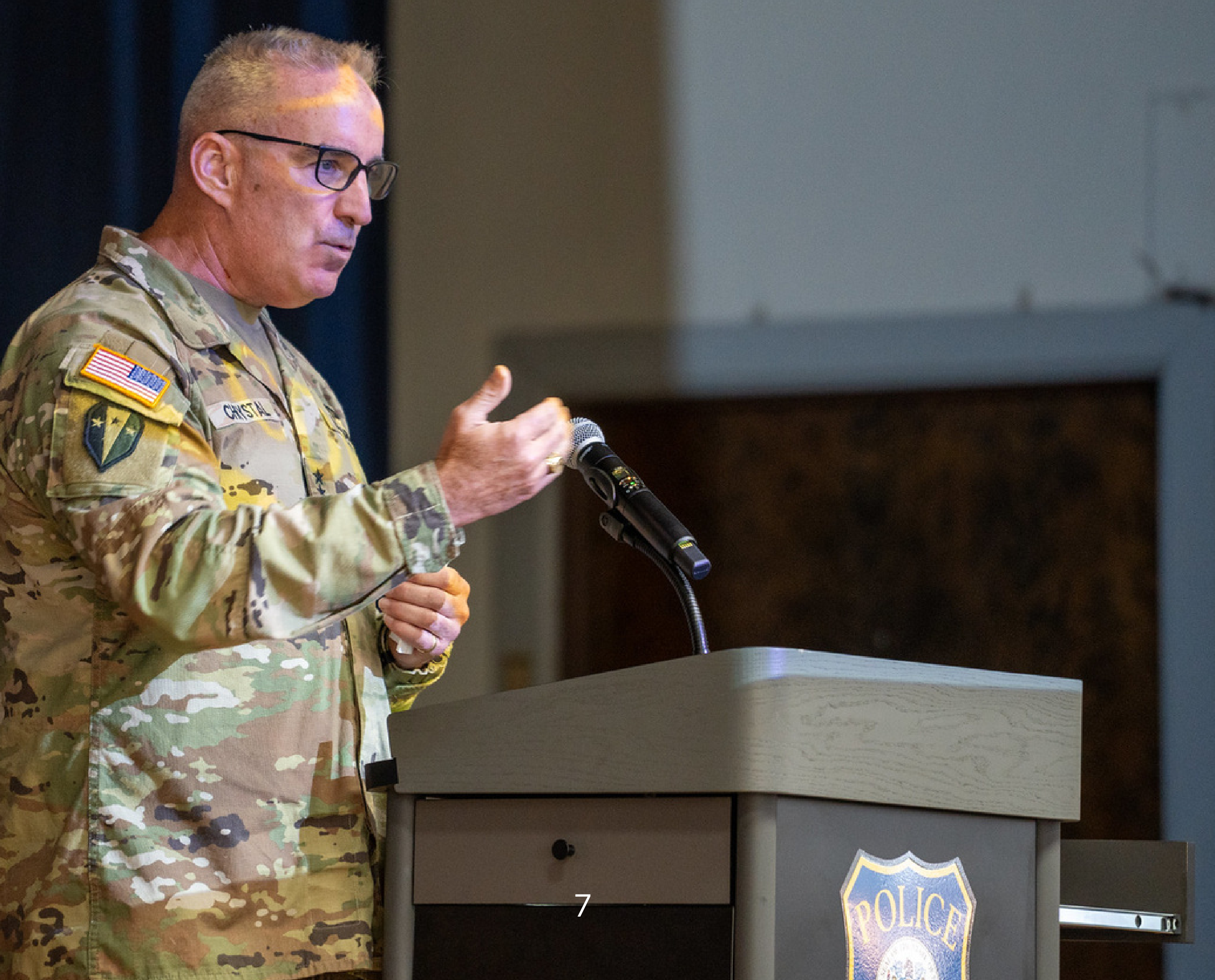 Military service member in uniform speaking at a podium with microphone during a Military Appreciation event