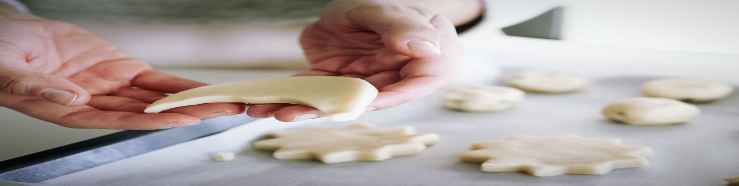 Hands preparing star and moon-shaped cookies on a baking sheet