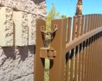 Close-up view of a gate hinge and latch area with a safety chain providing fall-over protection.