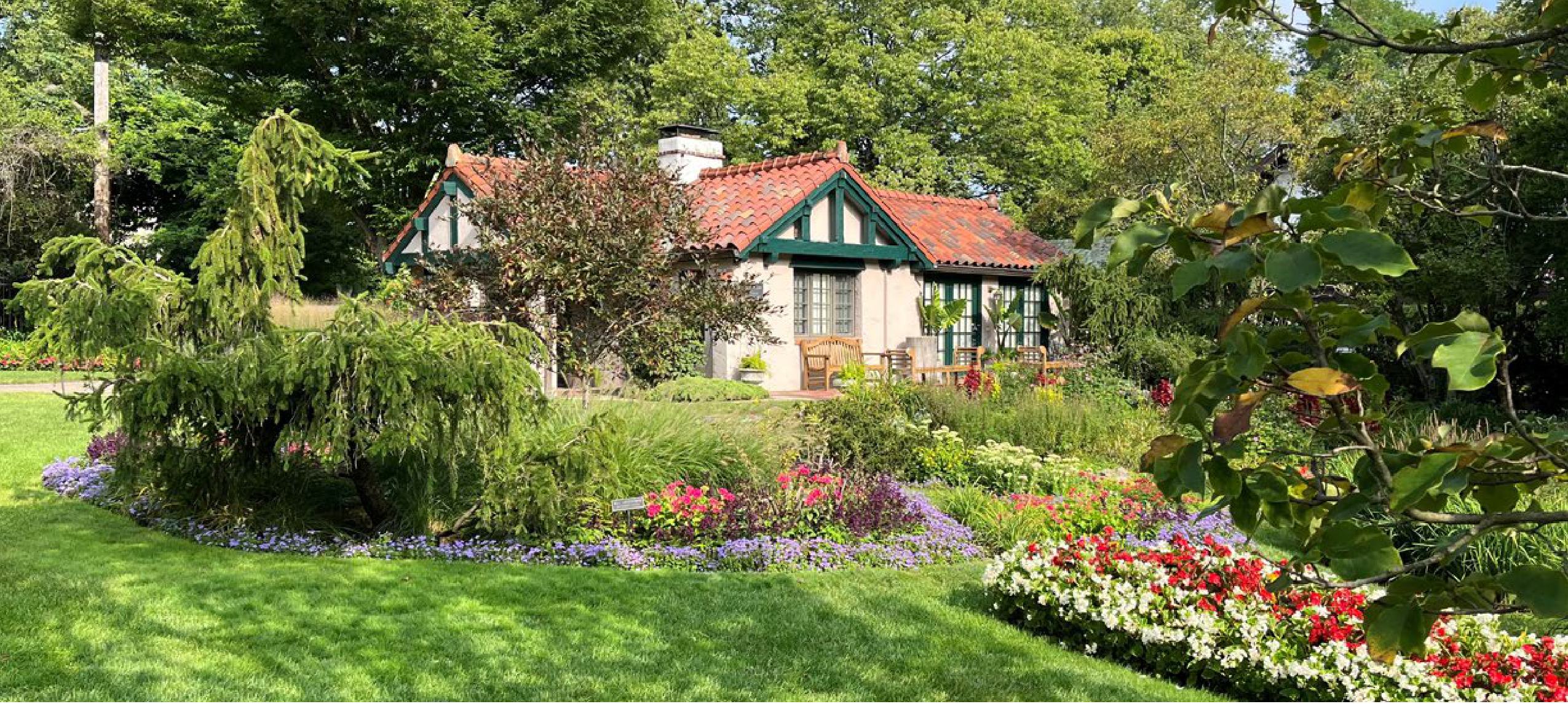 The Houk House cottage at Smith Gardens surrounded by flowering gardens and lush green lawn