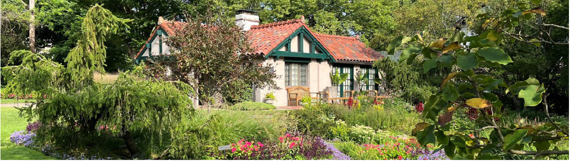 Smith Gardens house with terracotta roof surrounded by vibrant floral landscaping and lush trees