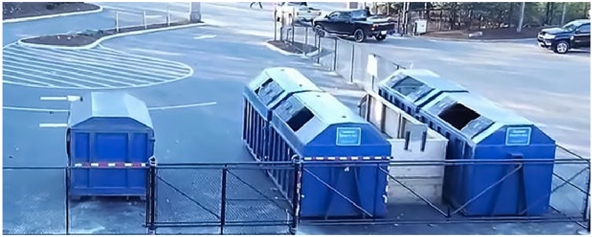 Drop-off dumpsters and recycling bins behind a fenced public works facility area