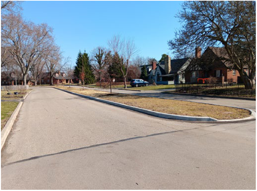 Completed landscaped median island with newly planted young trees on Harman Boulevard residential street