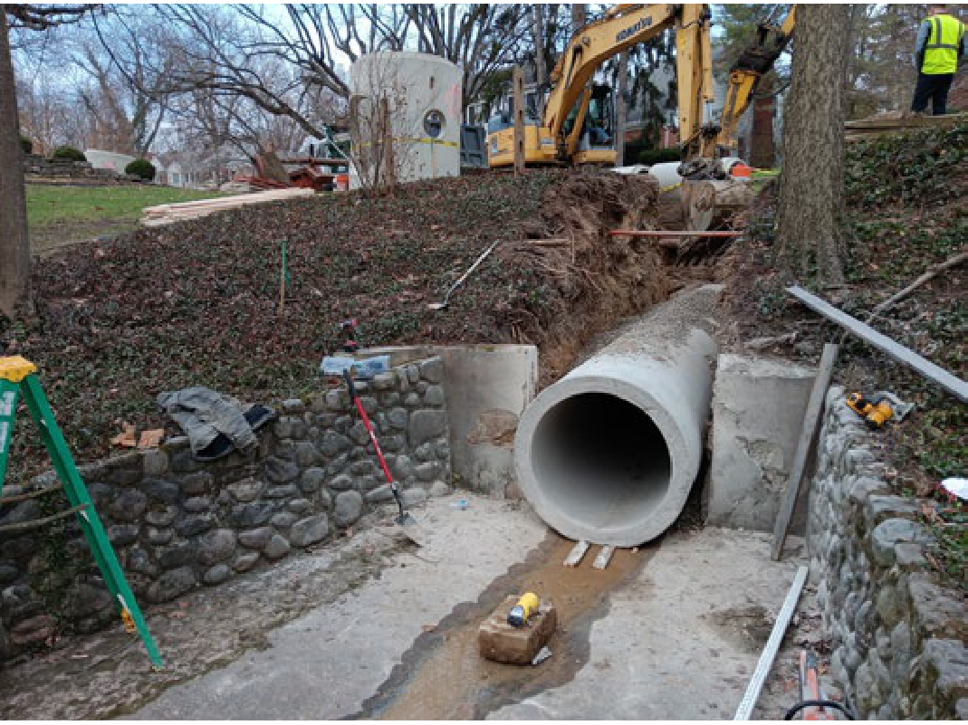 Excavation site during Far Hills Storm Sewer Reconstruction showing installation of a large concrete stormwater drainage pipe and stonework embankment