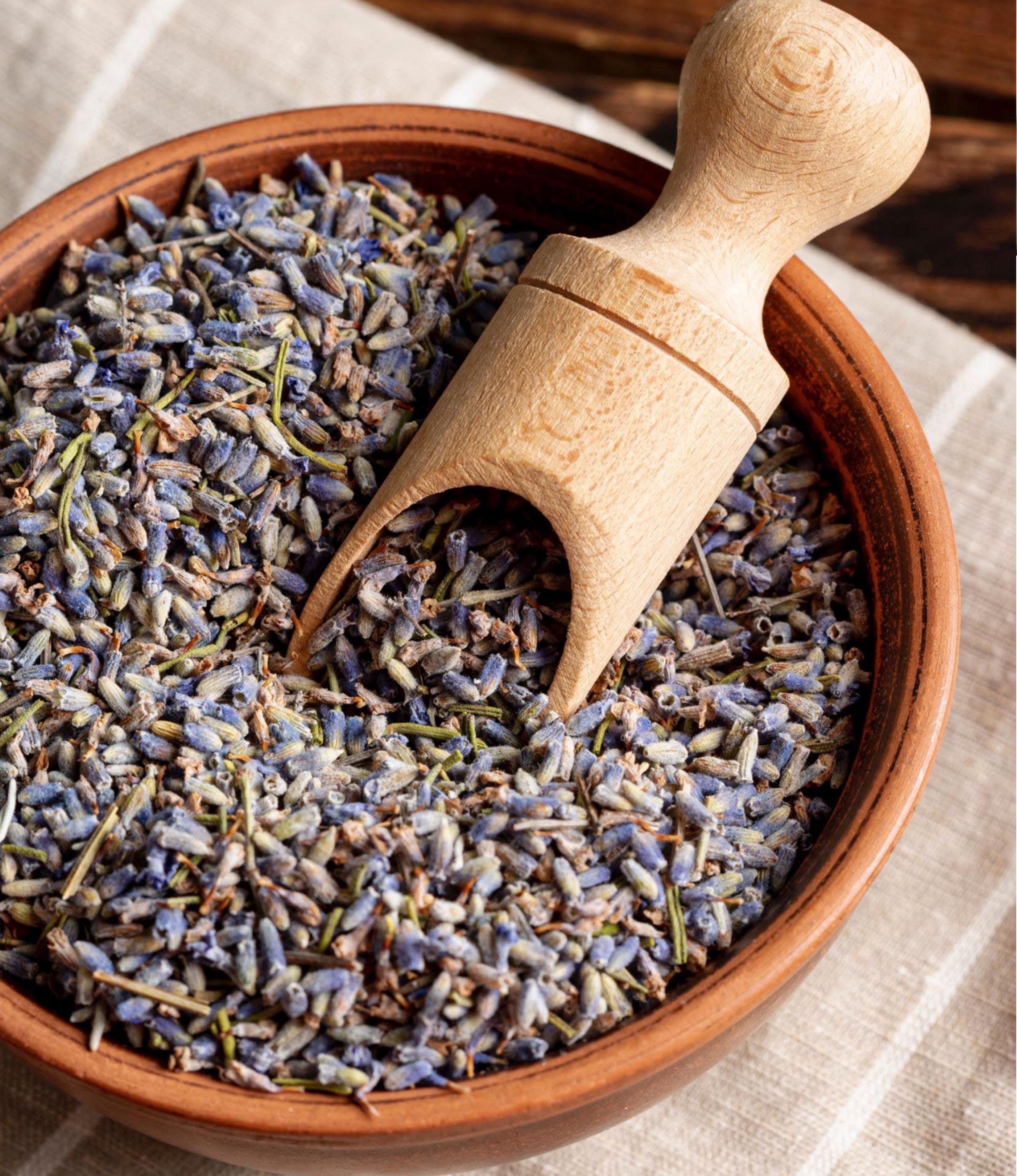 Lavender flowers in a clay bowl with a wooden scoop