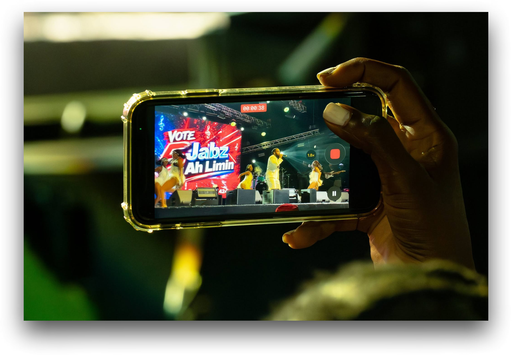 Audience member recording Jabz York performing live on stage with a smartphone