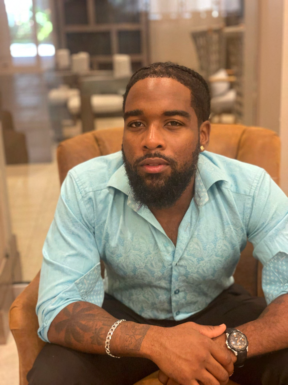 Jabz York seated in a brown armchair wearing a light blue button-down shirt
