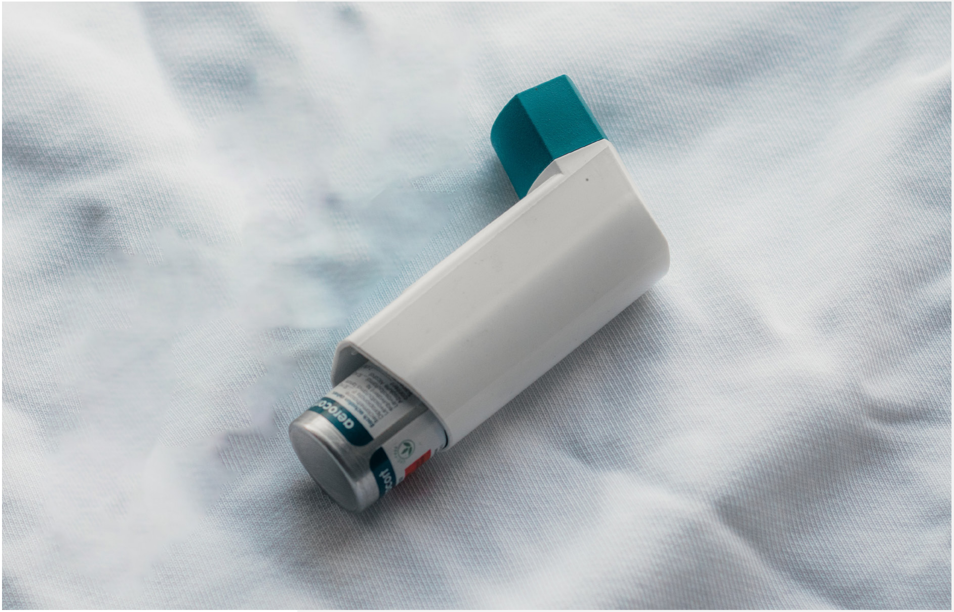 An inhaler lying on a white fabric surface.