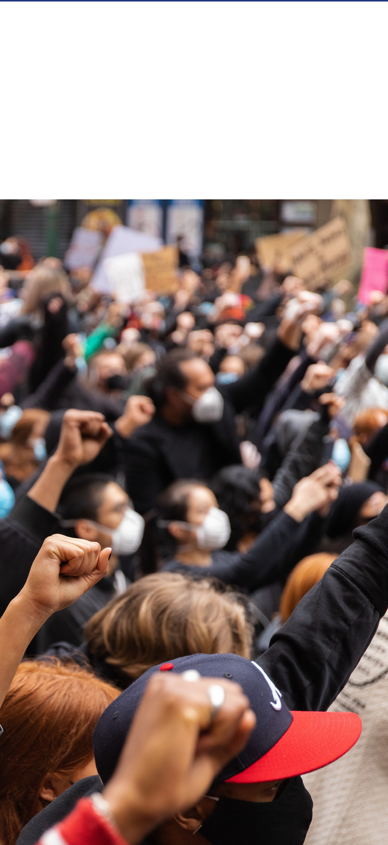 A large group of diverse people raising their fists in a crowd, symbolizing advocacy and collective action.