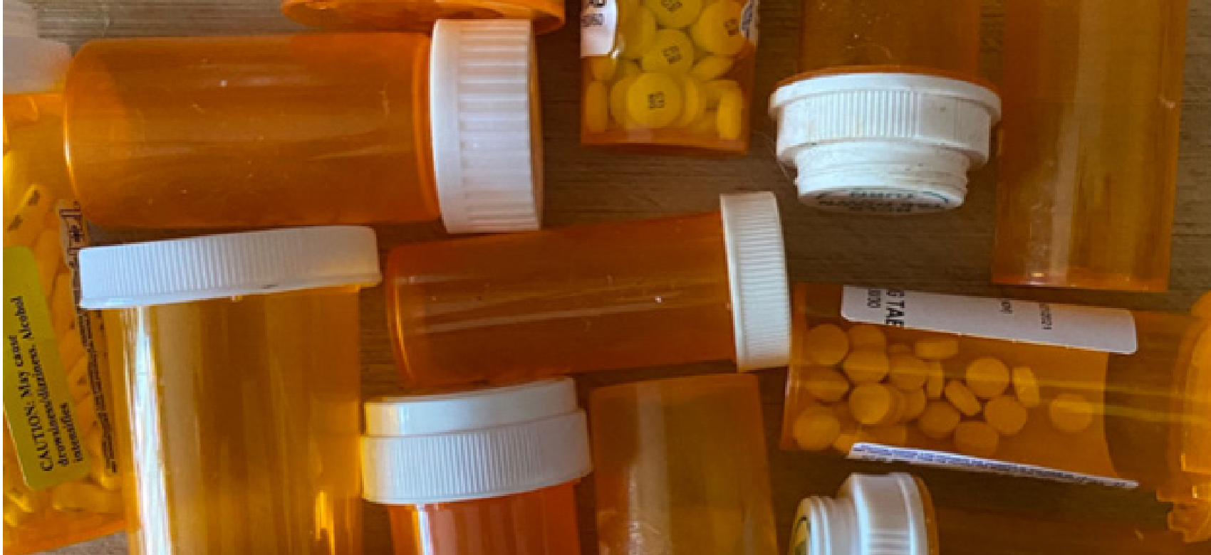 A shelf containing various over-the-counter medicine and supplement bottles including Ibuprofen, Lysine, and Apple Cider Vinegar gummies.