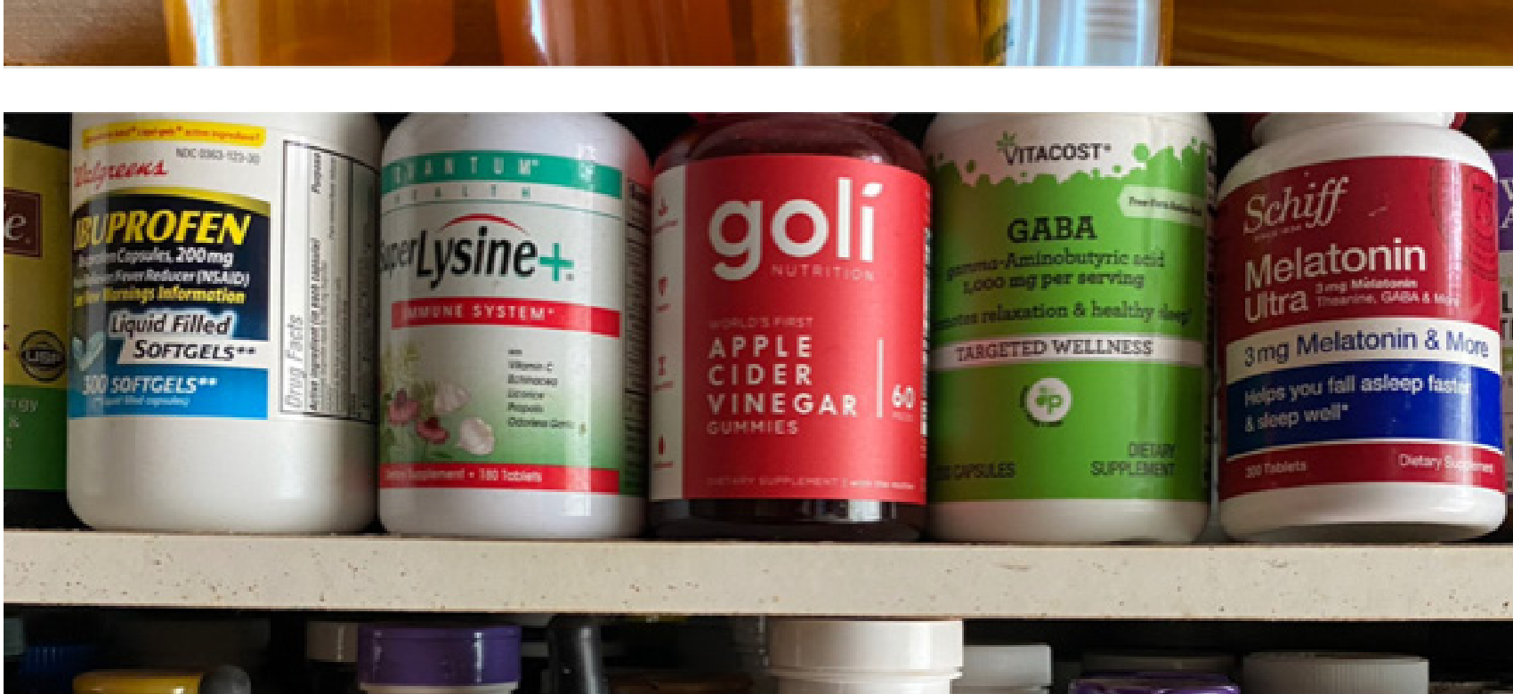 Bottles of dietary supplements including Acetyl L-Carnitine and Melatonin on a medicine shelf.