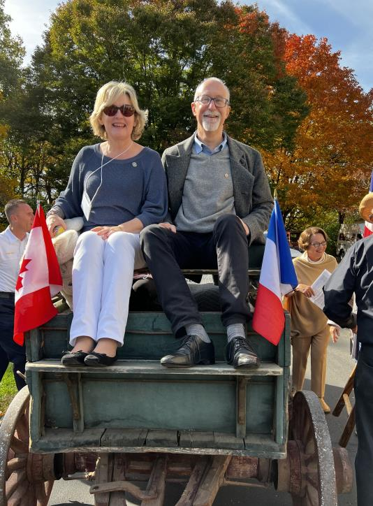 Couple seated on the back of a hayride wagon with Canadian and French flags