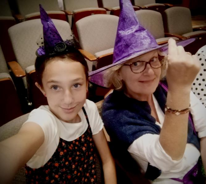 Two attendees wearing purple witch hats posing in theater seating