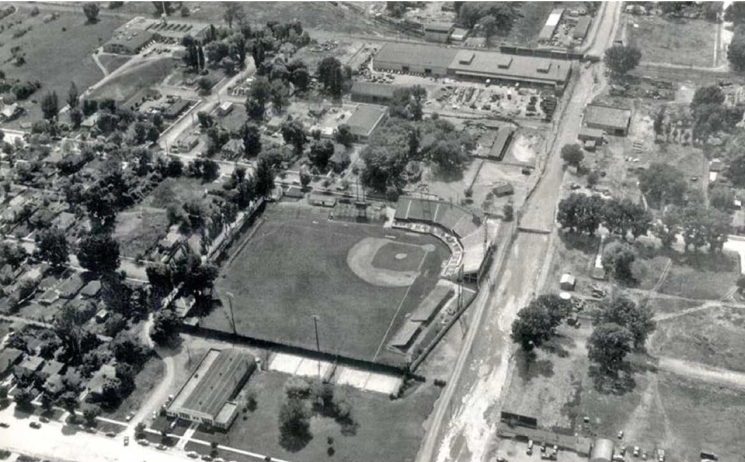 Historical 1952 aerial photograph of Derks Field baseball stadium surrounded by residential streets, open land, and daylit creek corridors in Salt Lake City.