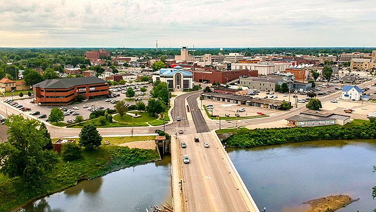 Aerial panoramic view of Muncie, Indiana showing the river, downtown skyline, and connecting bridge