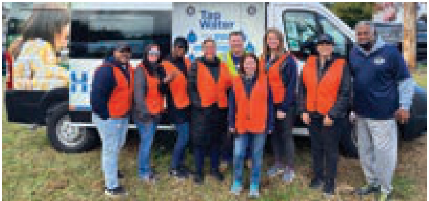 New Jersey American Water employees in orange safety vests posing in front of a Tap Water mobile van