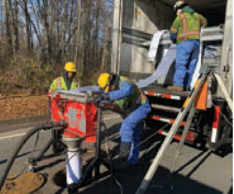 Workers lining sewer pipe with specialized equipment