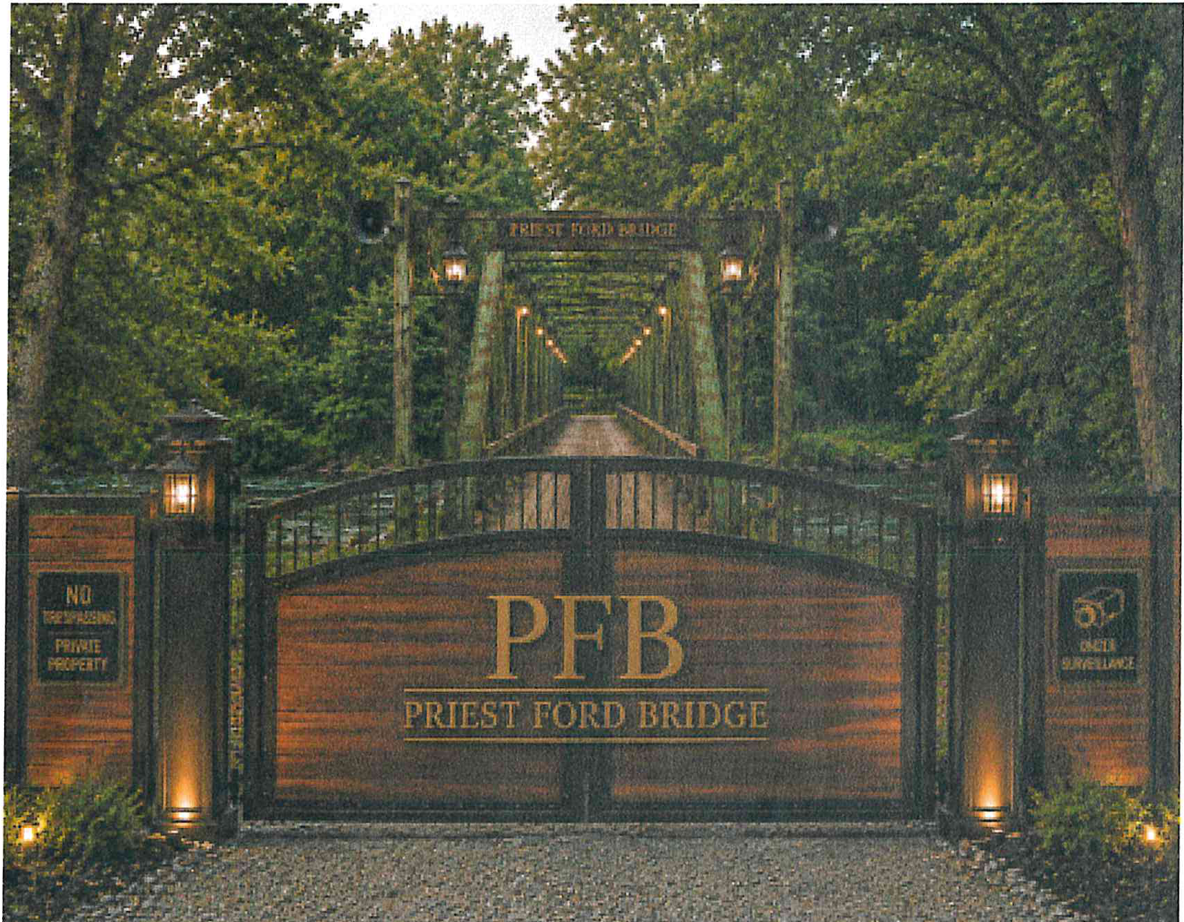 Priest Ford Bridge entrance featuring an ornamental wooden and iron security gate with PFB Priest Ford Bridge signage, illuminated stone columns, and the historic green truss bridge in the background surrounded by lush forest trees