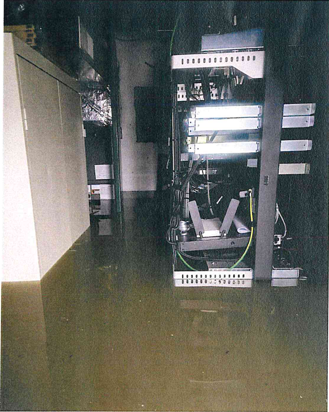 Flooded server room with communications equipment racks partially submerged in standing water